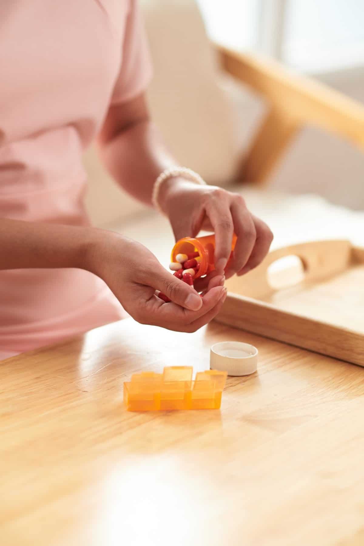 woman dispenses her medications from pill bottle